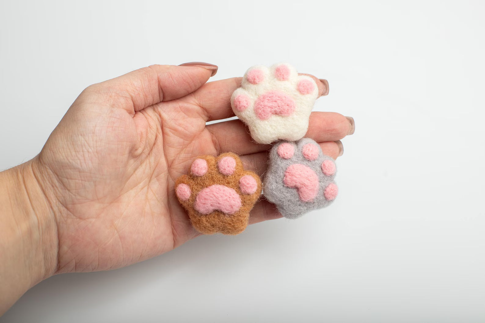 A soft white felt cat paw with pink pads for attached to a car air vent as a cute decorative clip or nature air freshener.