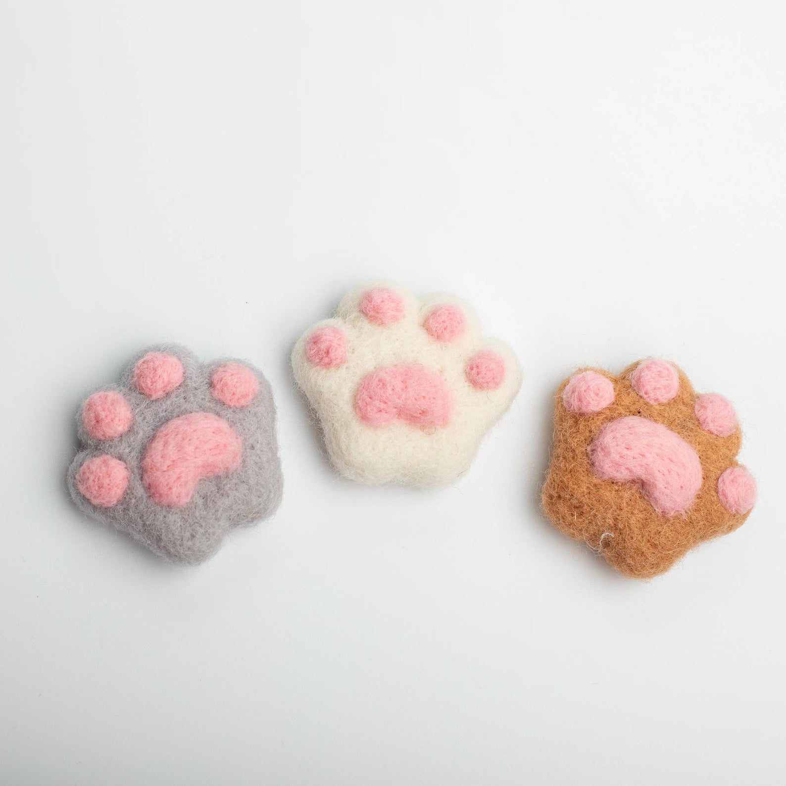 A soft gray, white, brown felt cat paw with pink pads for attached to a car air vent as a cute decorative clip or nature air freshener.