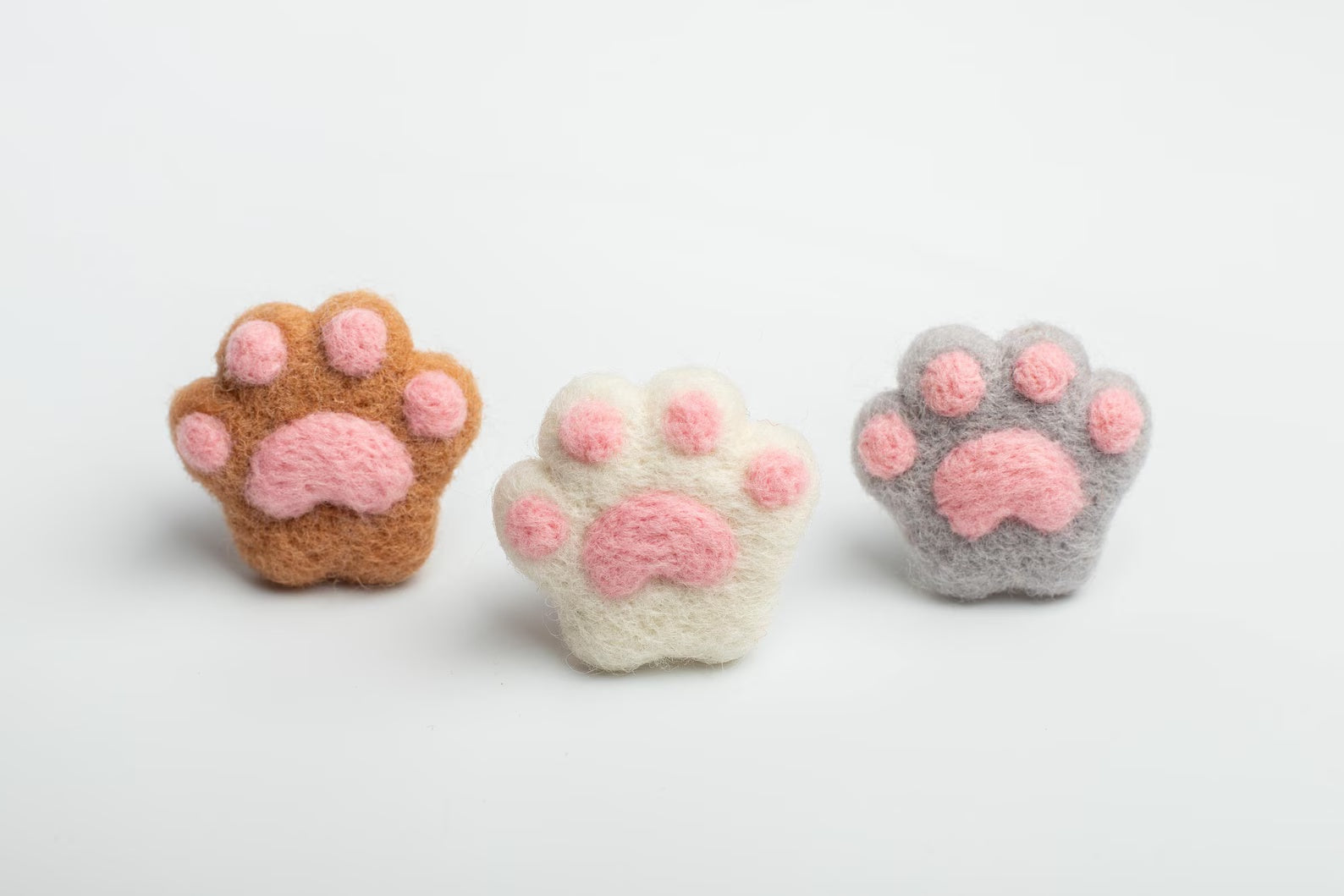 A soft three felt cat paw with pink pads for attached to a car air vent as a cute decorative clip or nature air freshener.