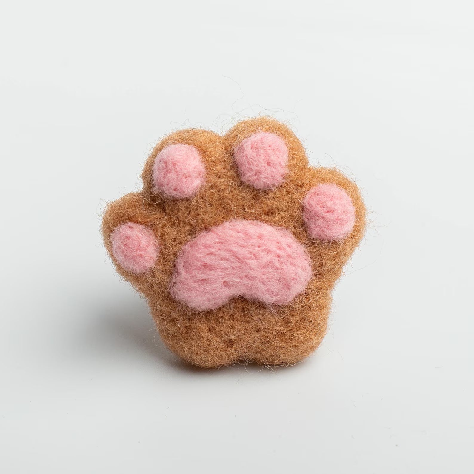 A soft brown felt cat paw with pink pads for attached to a car air vent as a cute decorative clip or nature air freshener.