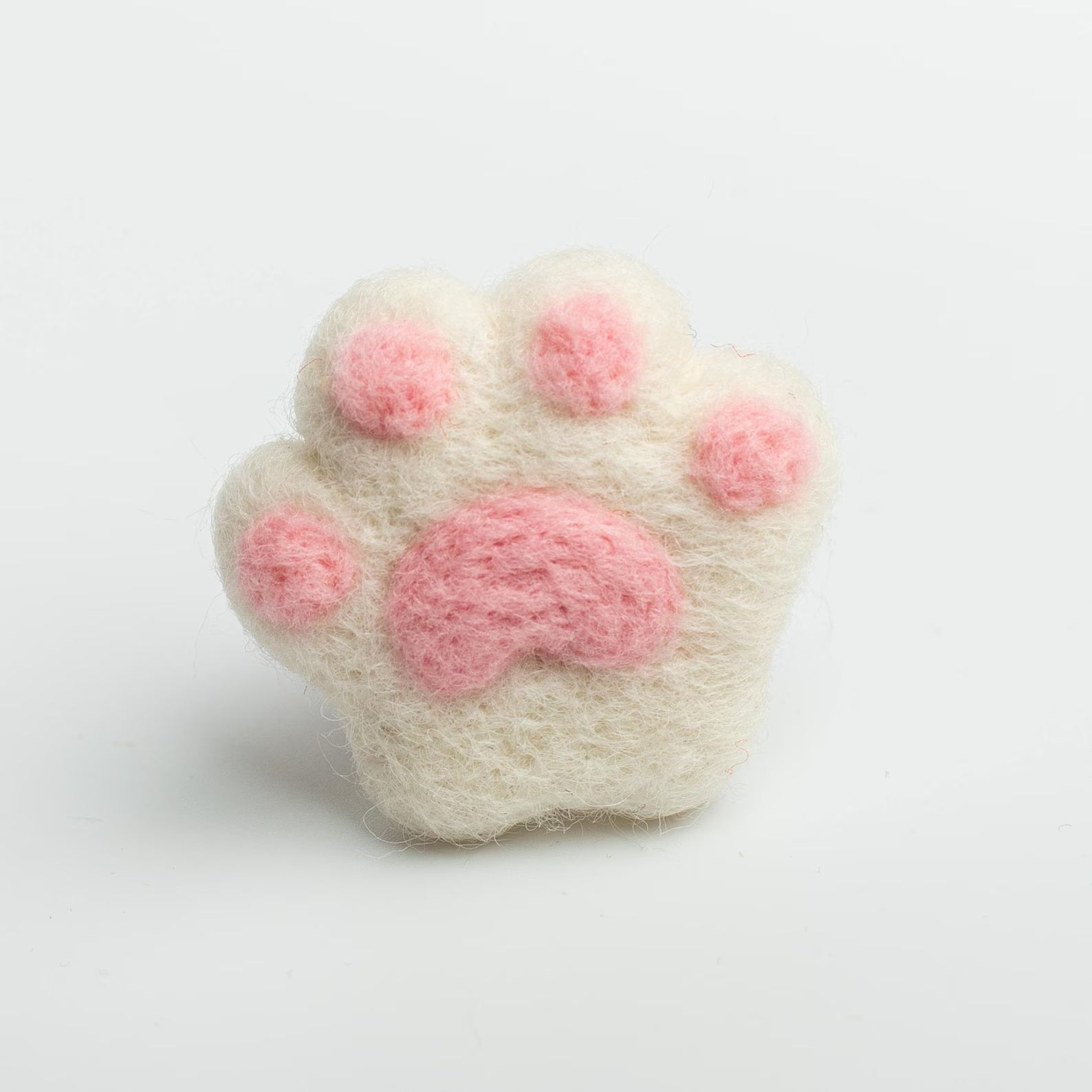 A soft white felt cat paw with pink pads for attached to a car air vent as a cute decorative clip or nature air freshener.