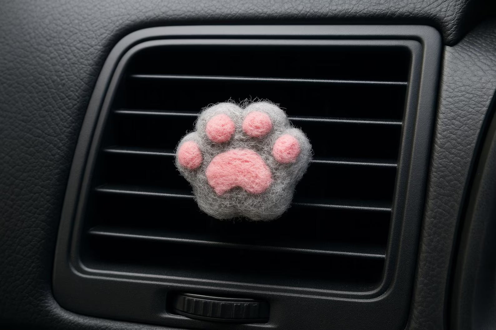 A soft gray felt cat paw with pink pads for attached to a car air vent as a cute decorative clip or nature air freshener.