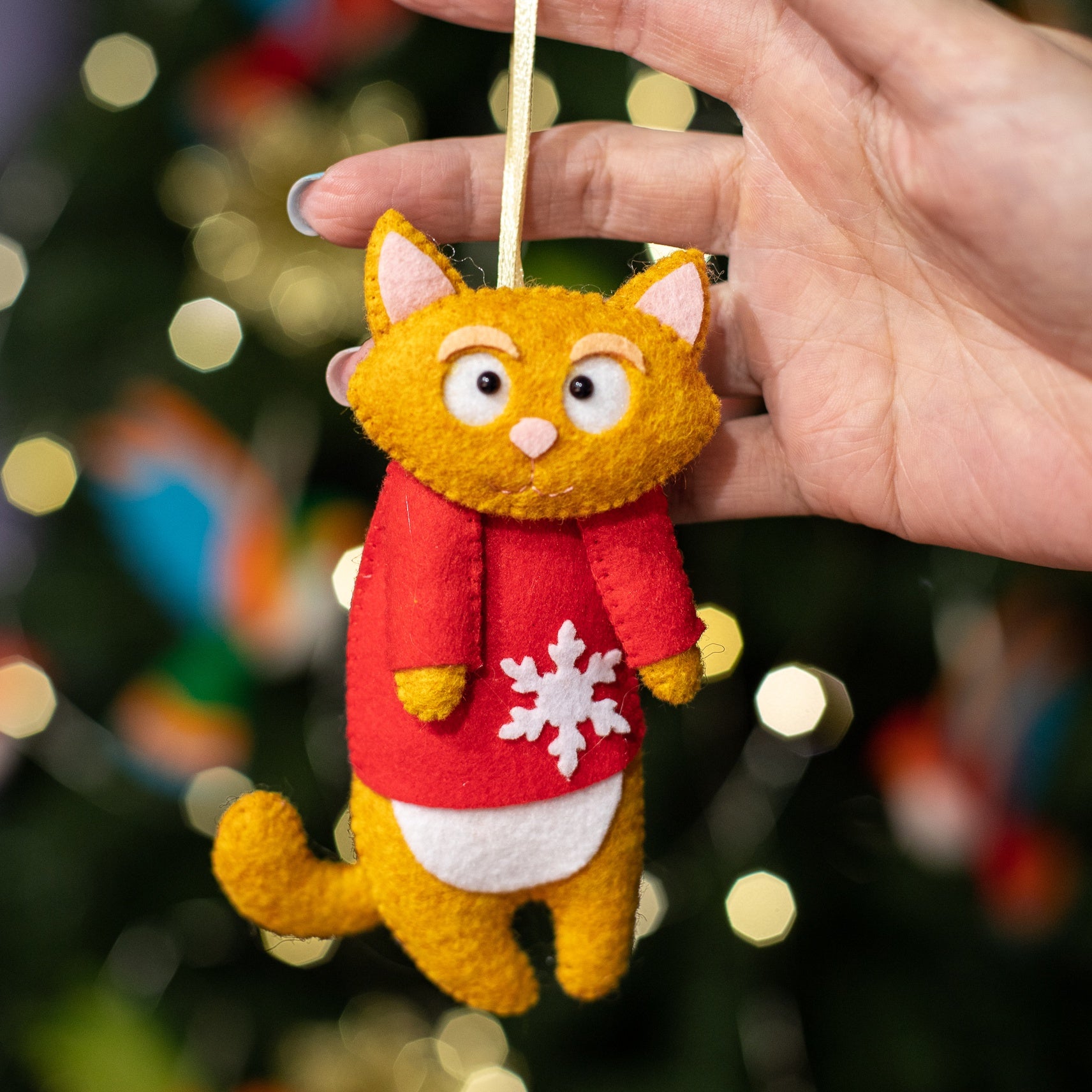 Felt cat ornaments wear in festive red sweater with a snowflake.